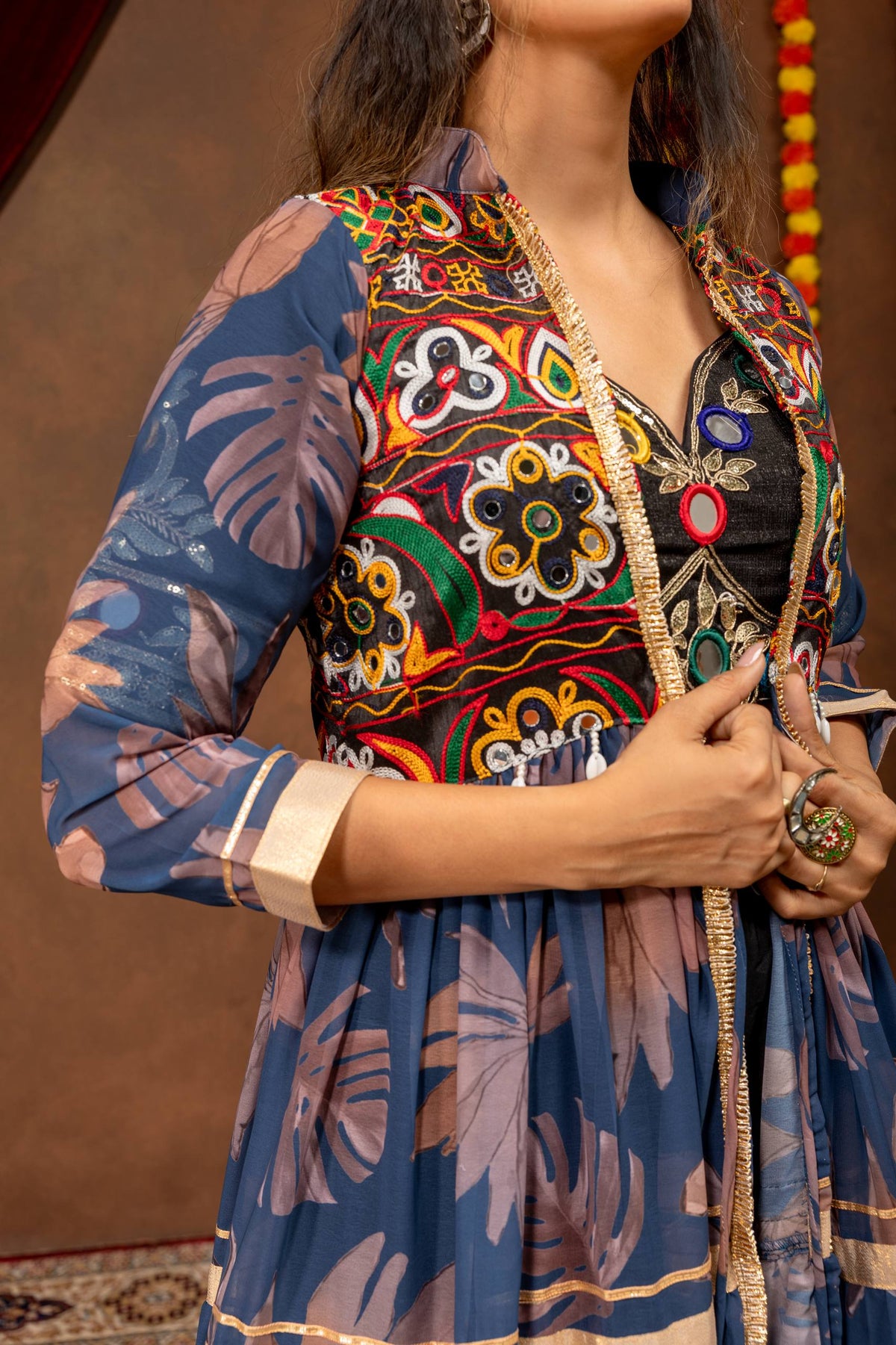 Mid-shot side angle highlighting the mirror work and thread embroidery on the bodice yoke of a blue printed long shrug.
