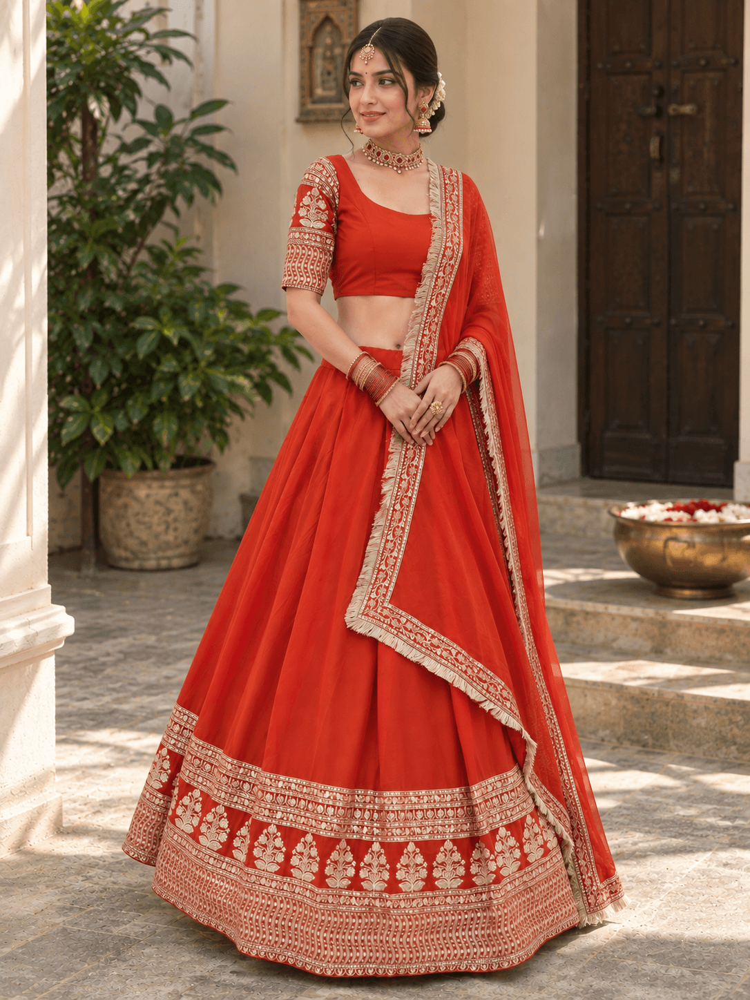 Three-quarter view of orange embroidered chaniya choli set highlighting the hanging fringe dupatta border