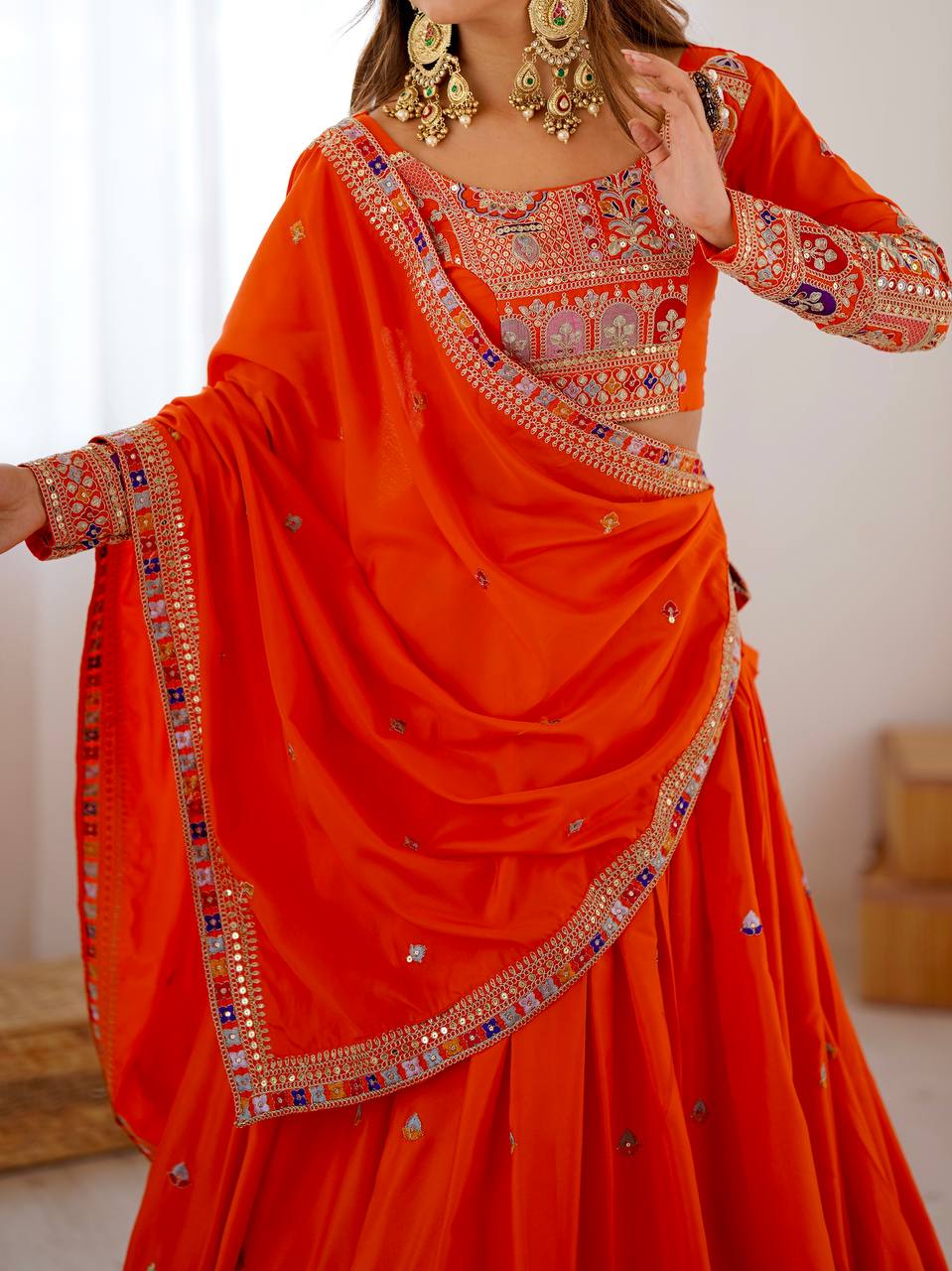 Close-up shot of orange choli blouse neckline embroidery and draped dupatta with detailed border embellishments
