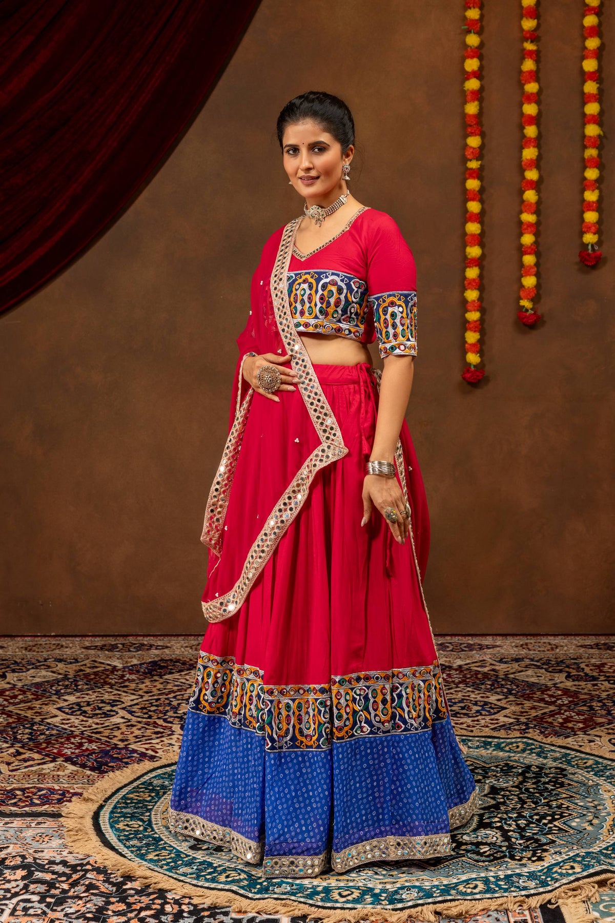 Full-length view of model posing in pink and blue lehenga choli with mirror work border dupatta