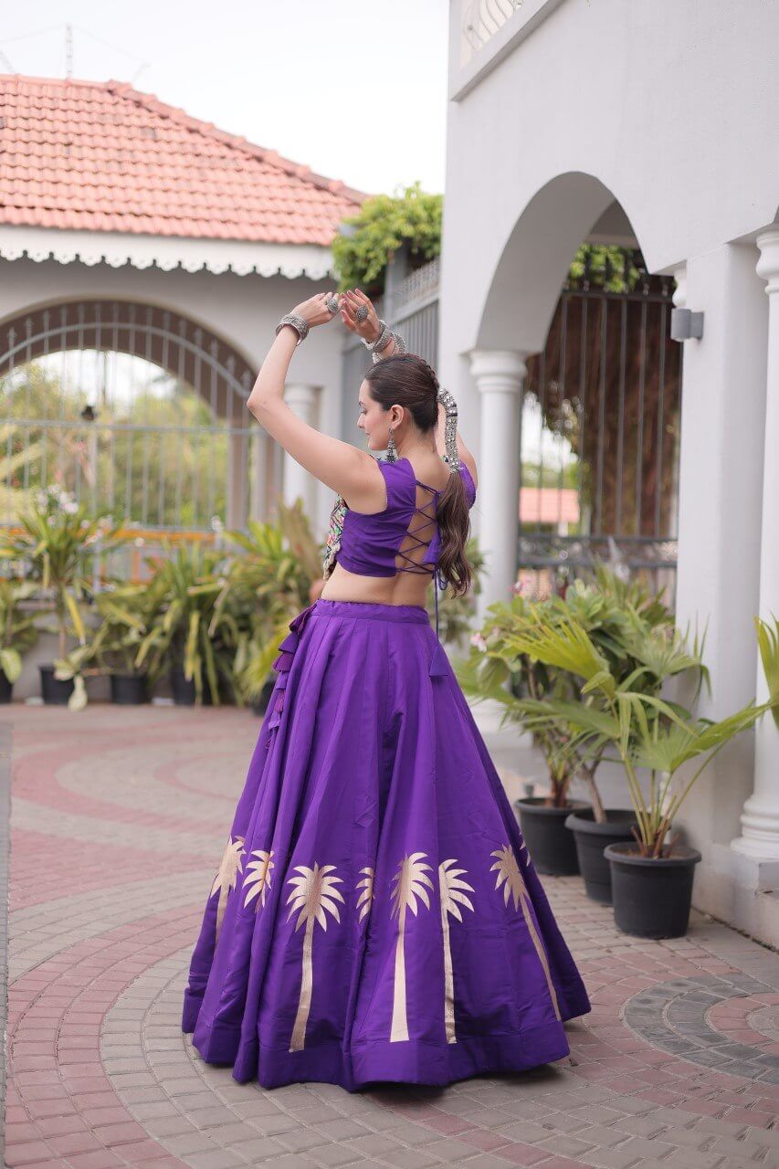 Back view of purple lehenga choli featuring lace-up blouse and gold palm tree border