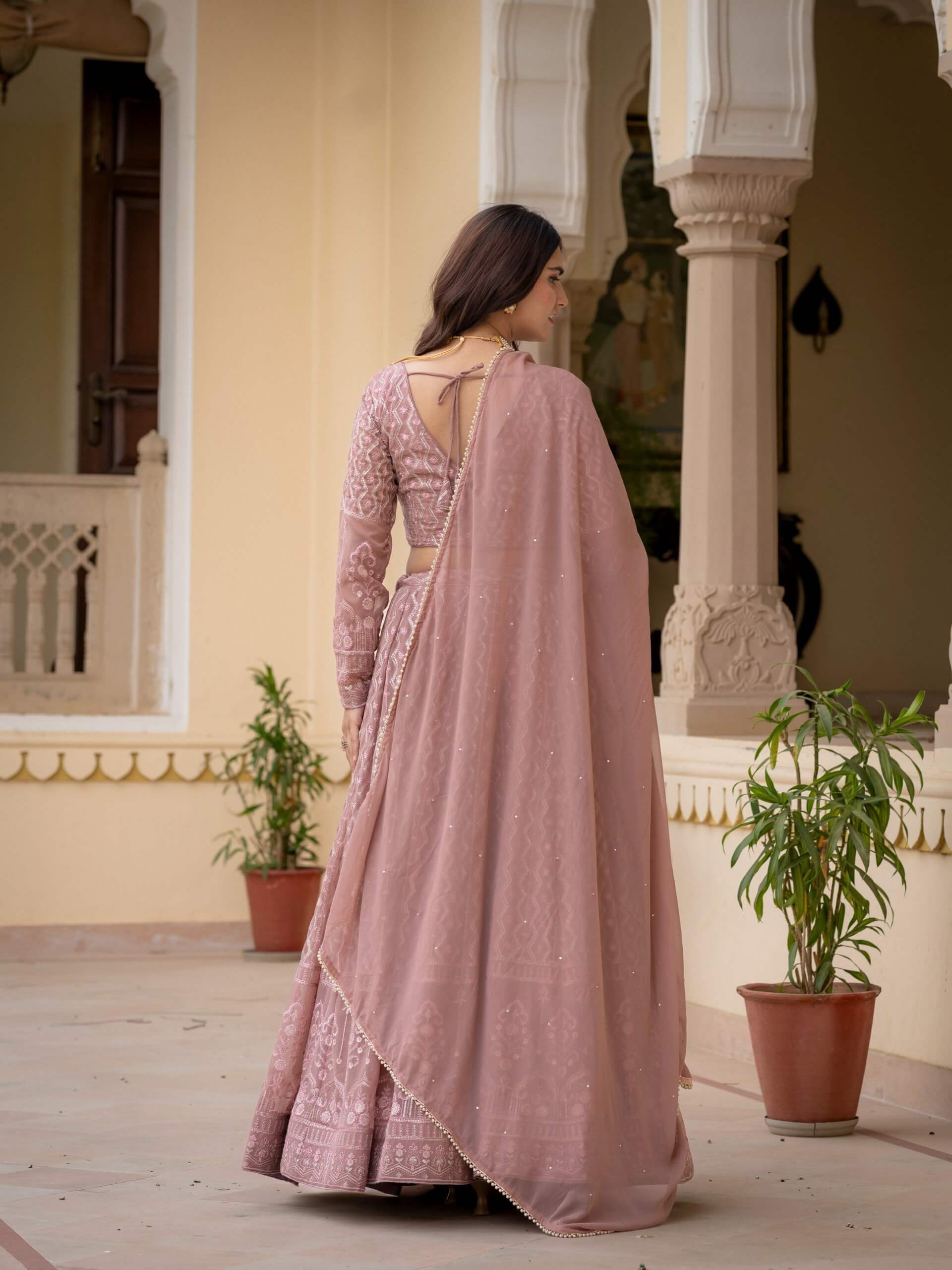 Rosy brown embroidered lehenga choli with sheer dupatta shown from the back