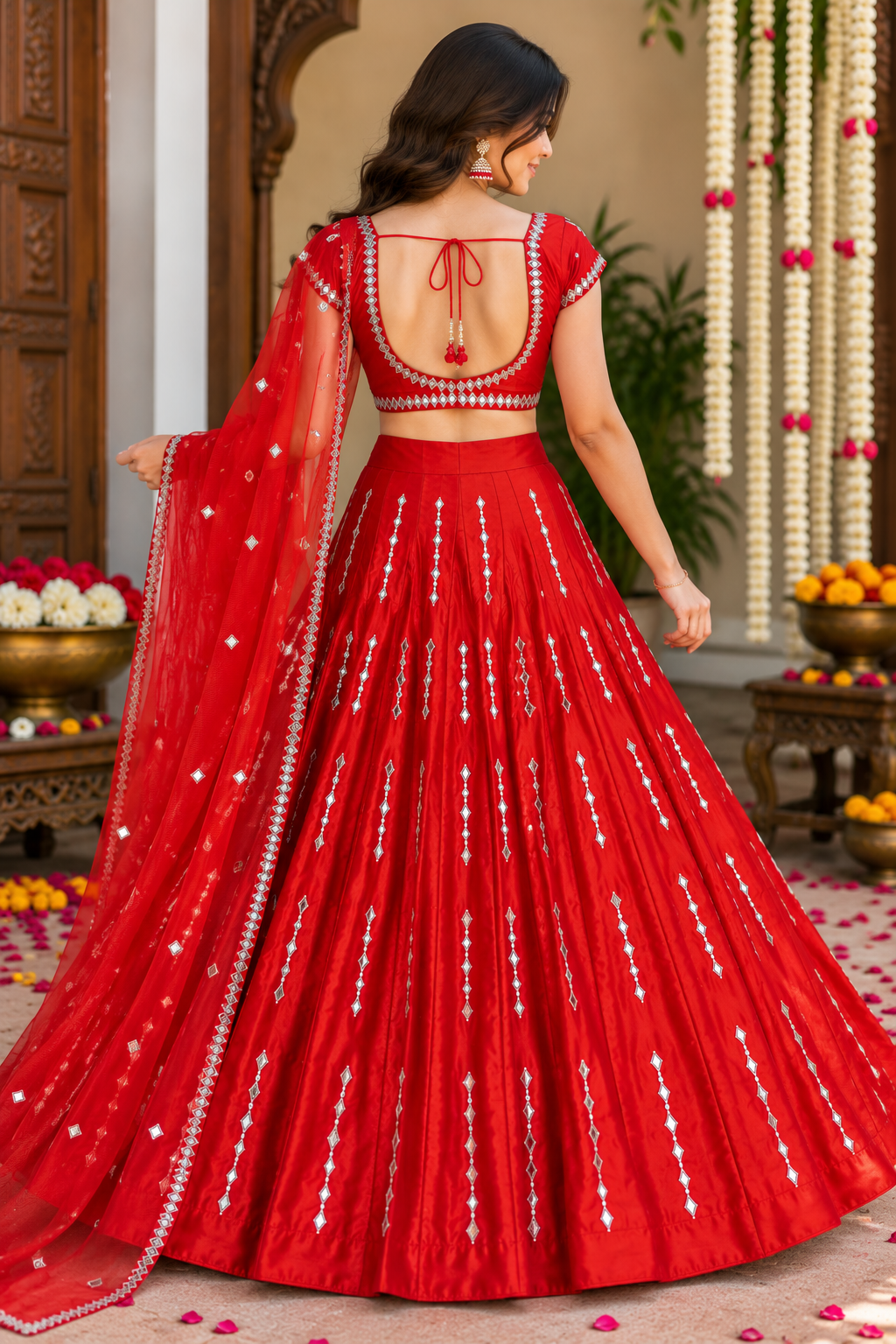 Full-length back view of a model in a red flared lehenga highlighting the deep square-back cutout blouse with tie-up dori tassels.