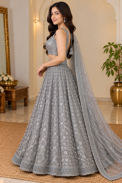 Side profile full-length view showing the circular silhouette, geometric diamond jaal, and draped sheer dupatta of a silver-grey lehenga.