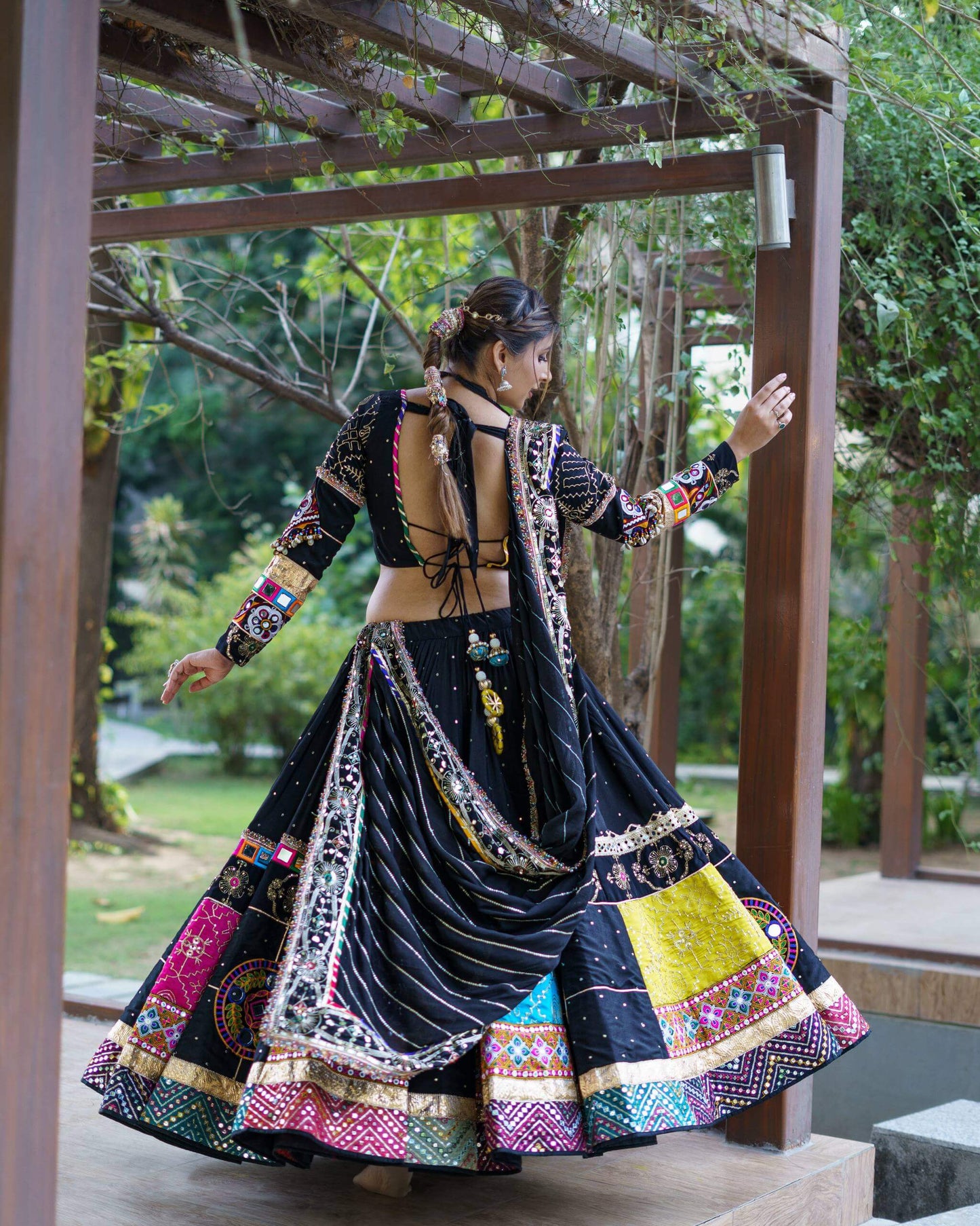 Back view of model wearing a black chaniya choli with tie-up backless blouse and draped dupatta across the flared skirt