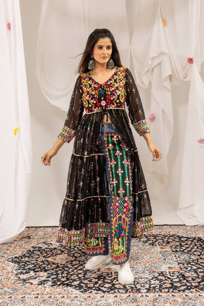 Standing full-length front view of model wearing a black long jacket shrug over blue denim pants with Radha Krishna folk embroidery