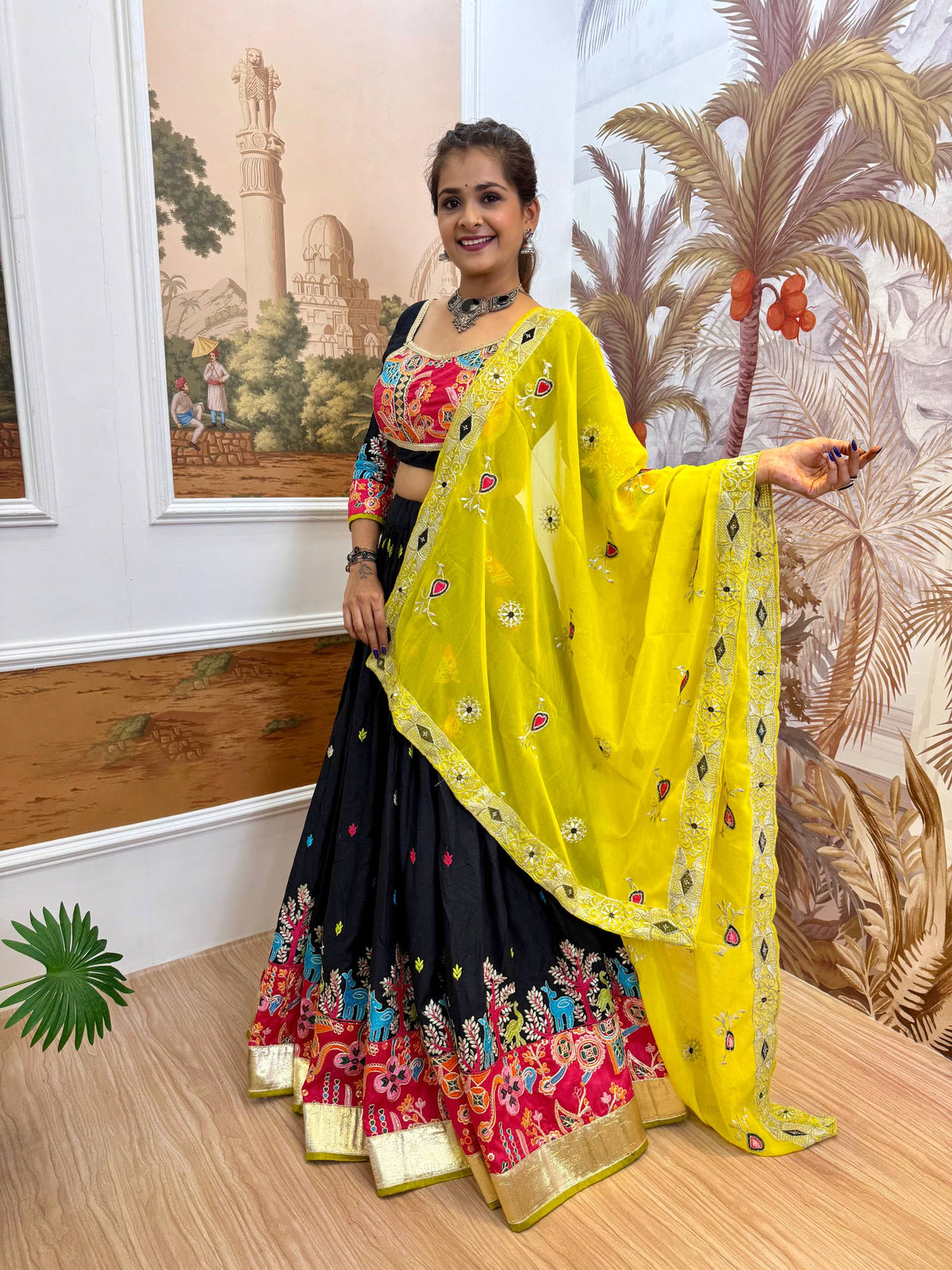 Side-angle full-length shot showing the wide flare, pink patterned hem, and gold zari border of a black lehenga skirt