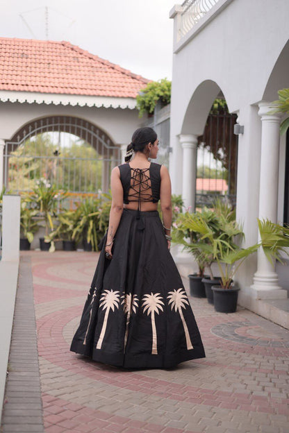 Back view of a black lehenga with beige floral motifs and a lace-up black blouse