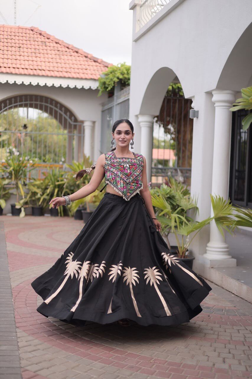 Black lehenga choli shown while twirling, featuring multicolor blouse work and beige floral motifs on the skirt