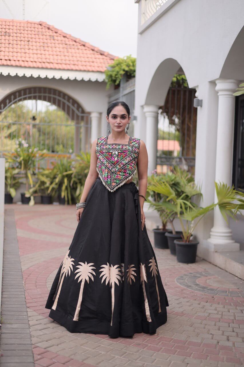 Front view of a black lehenga choli with a multicolor patterned blouse and beige floral skirt motifs