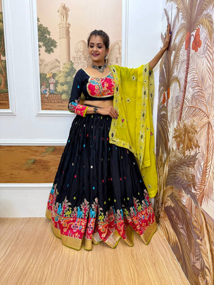 Full-length view of model in a black lehenga and black scoop-neck blouse with pink embroidered yoke patch and bright yellow dupatta