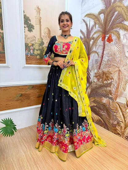Full-length front view of a model wearing a black pleated lehenga with multi-color animal and floral border, paired with a bright yellow dupatta