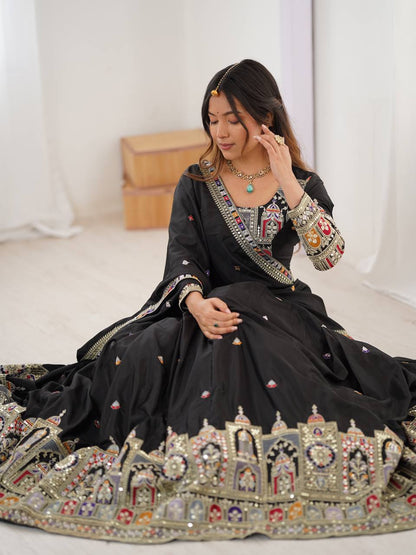 Seated view of model showing detailed border embroidery and embellishments on a black flared lehenga