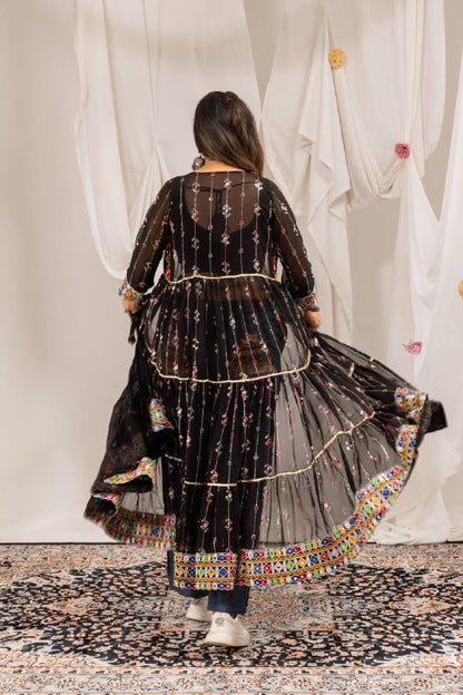 Full-length back view showing the gathered tiered flare and mirror-work border of a sheer black long jacket shrug