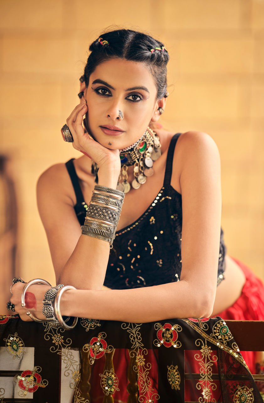 Close-up portrait of model wearing a black sleeveless sequined crop blouse styled with heavy oxidized tribal silver jewellery