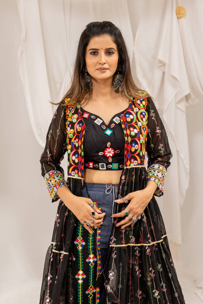 Mid-shot view of a model in a black sweetheart crop top embellished with shells, under a colorful mirror-work shrug