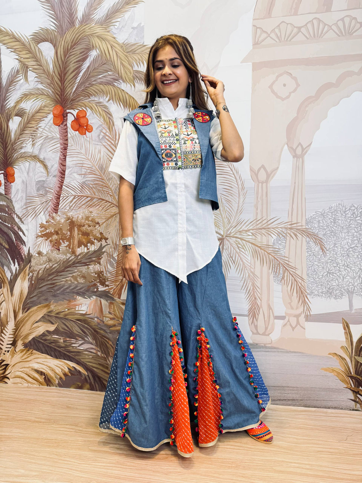 Full-length standing pose of model in a white pointed-hem shirt, blue short jacket, and wide-leg sharara pants