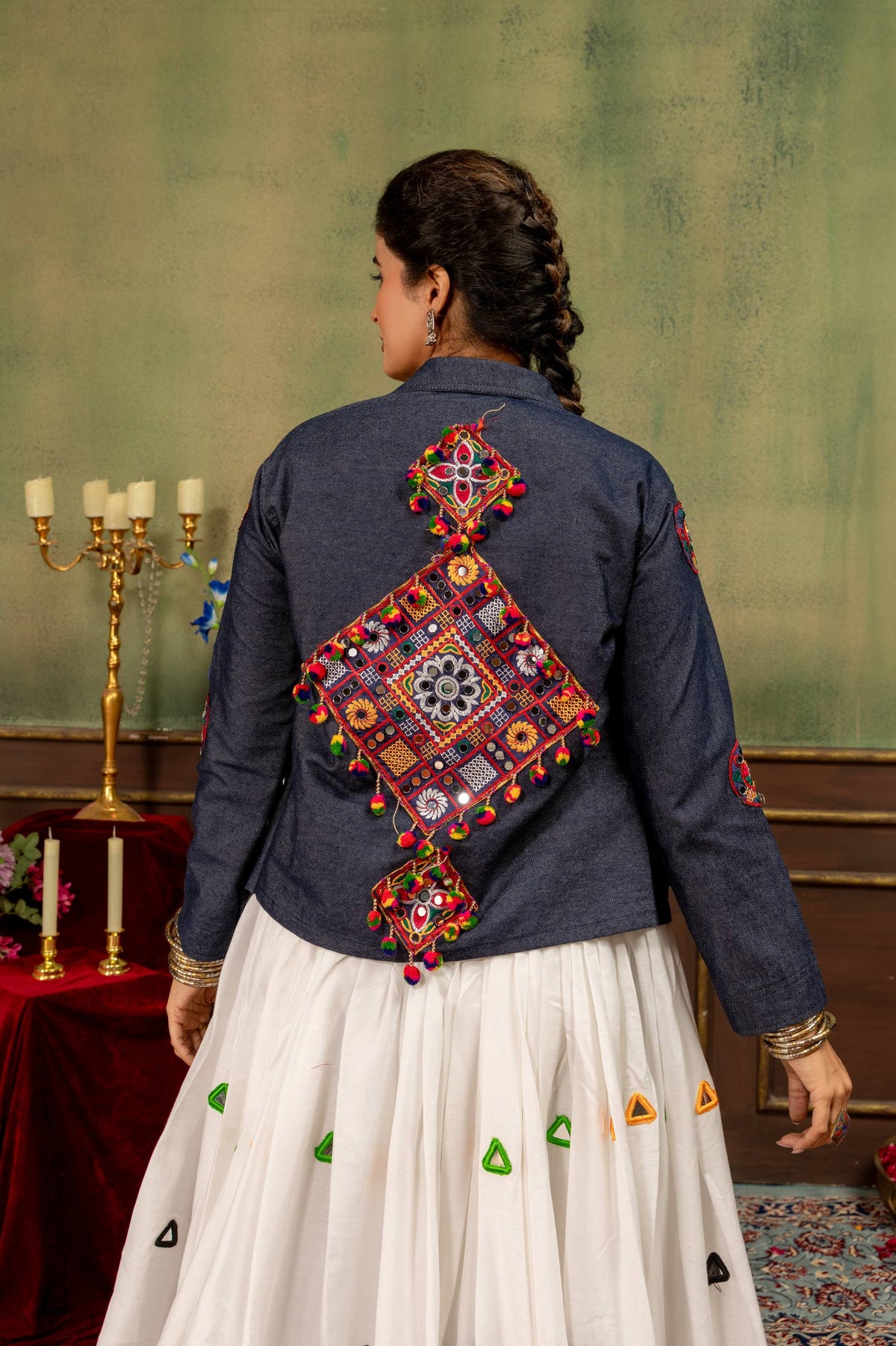 Back view of model wearing denim blue jacket featuring colorful geometric Kutchi-style mirror embroidery