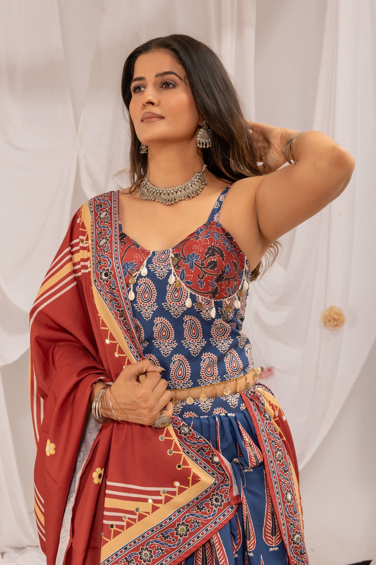 Close-up view of model wearing blue printed noodle-strap blouse embellished with cowrie shells and coins