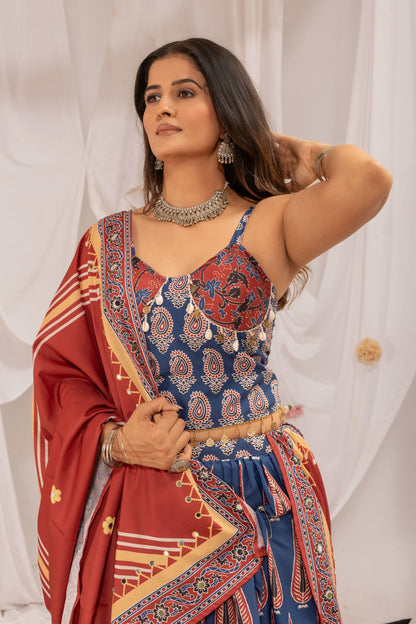 Close-up view of model wearing blue printed noodle-strap blouse embellished with cowrie shells and coins