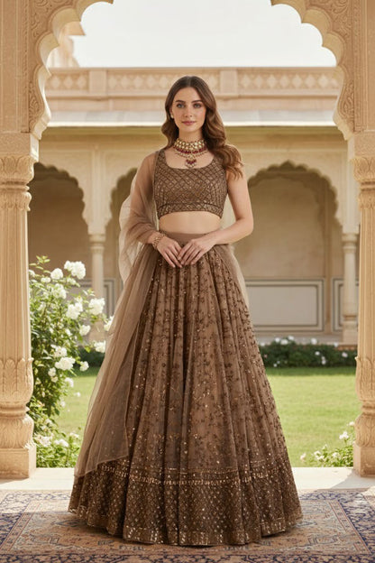 Full-length shot of a model posed in a heritage courtyard wearing an embellished coffee brown lehenga choli set with matching net dupatta.