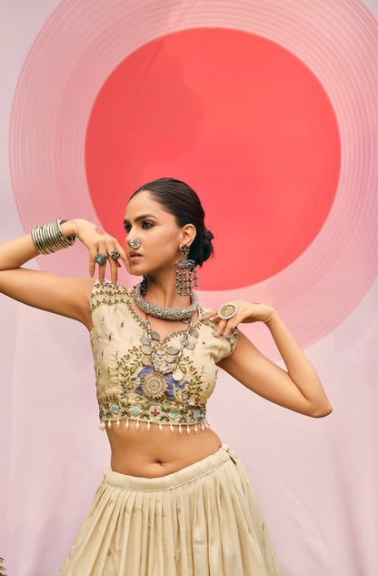 Mid-shot view of a cream sleeveless blouse with elephant embroidery and pearl drop fringe hem, styled with oxidized jewellery