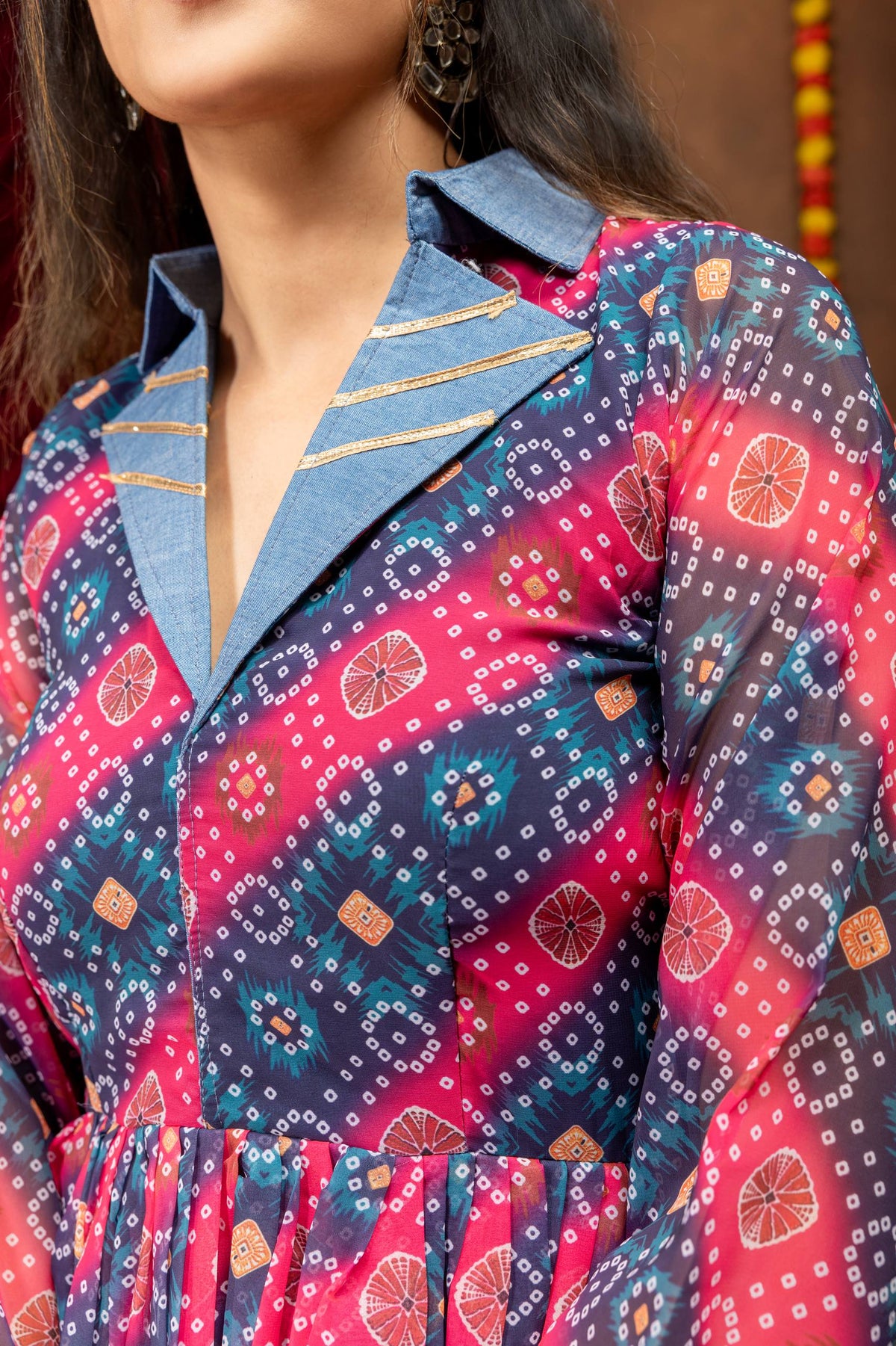 Close-up view of light blue denim notch lapel collar with gold gota lines on a pink and navy bandhani printed top