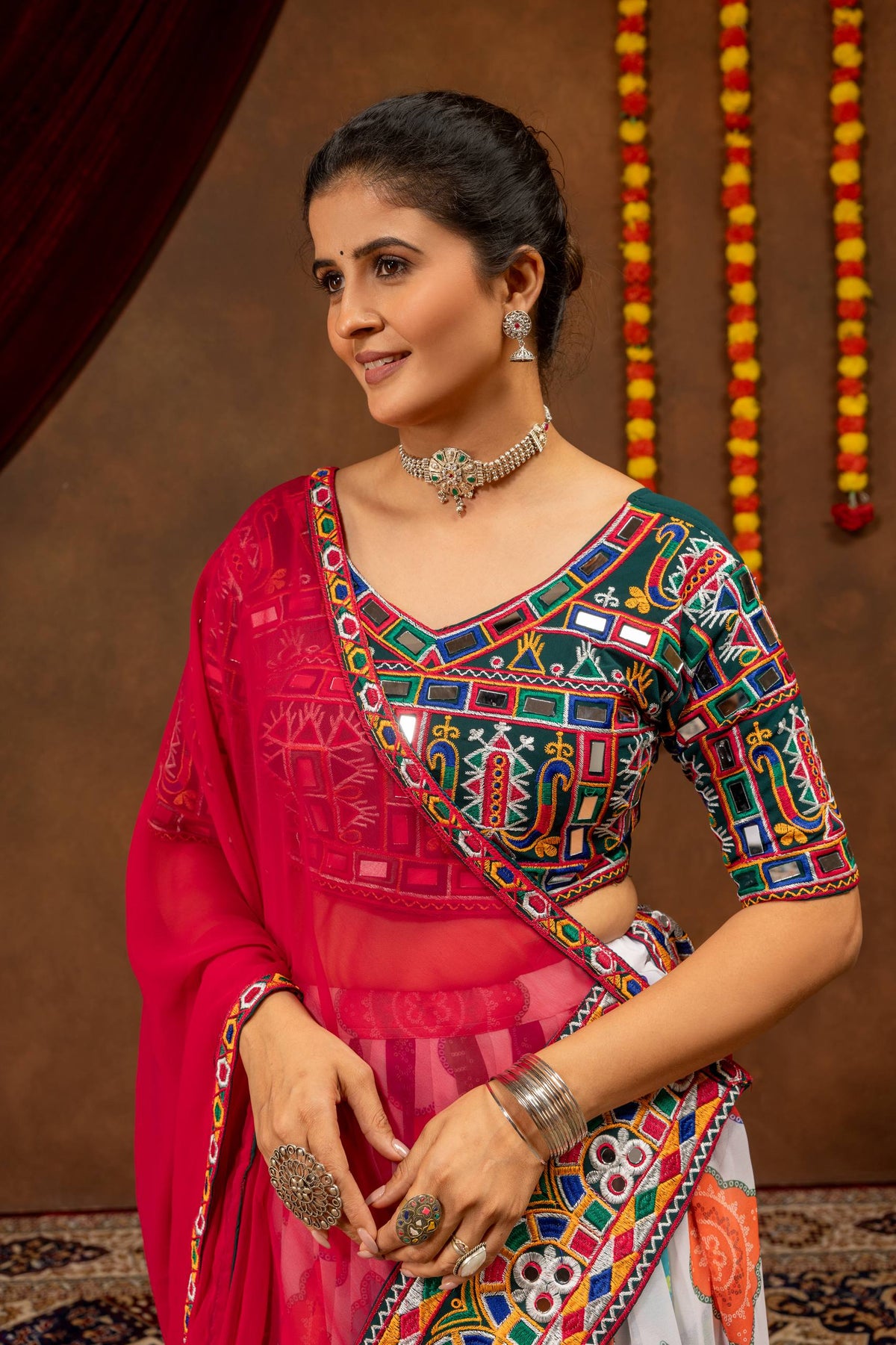 Close-up view of dark green blouse featuring colorful Kutchi mirror embroidery paired with pink dupatta