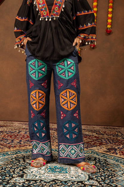 Close-up front view of wide-leg blue jeans adorned with colorful geometric floral patches and mirror work embroidery