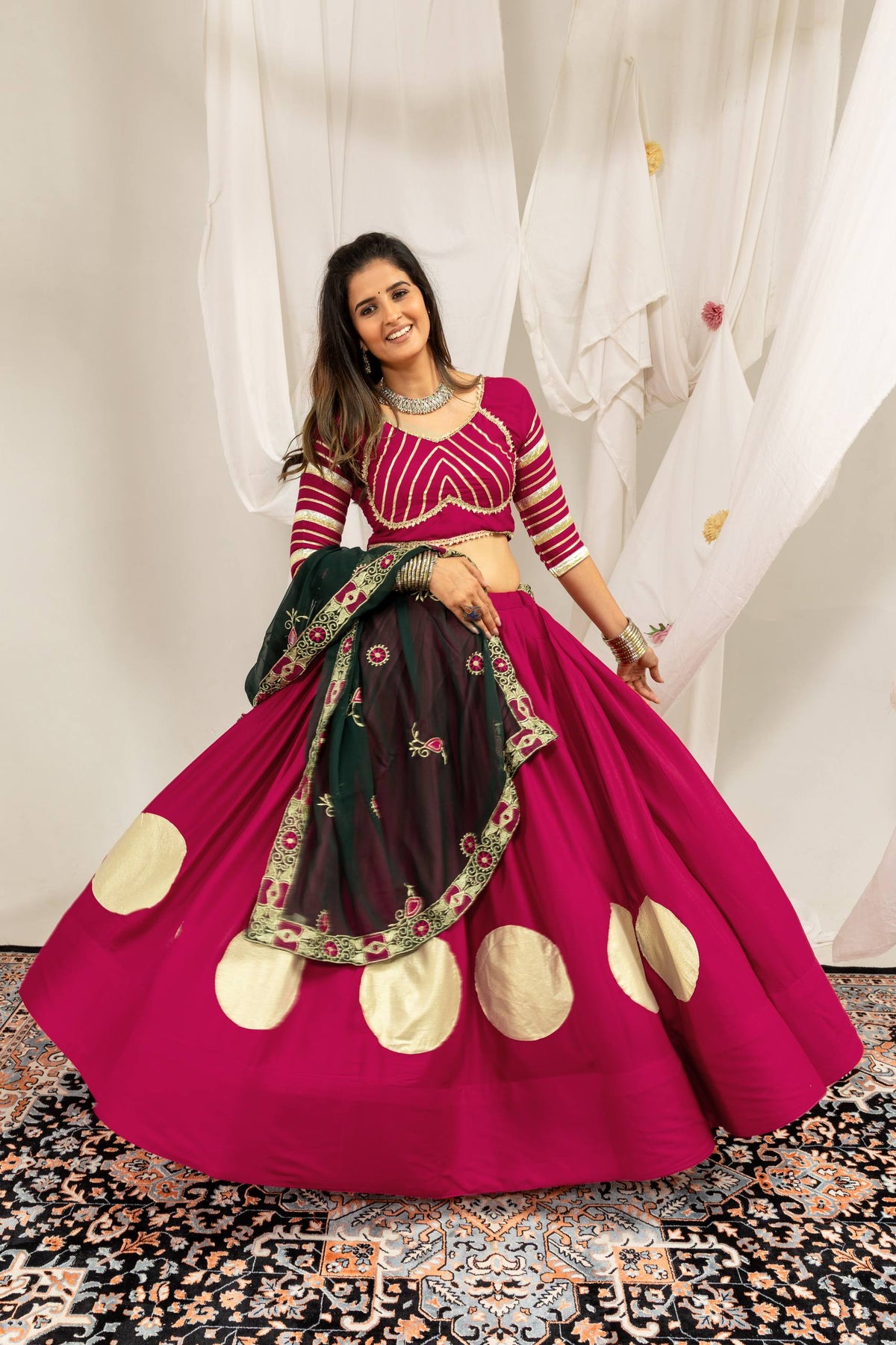 Wide flare display of a magenta lehenga skirt featuring large gold circular prints and a matching elbow-sleeve choli.