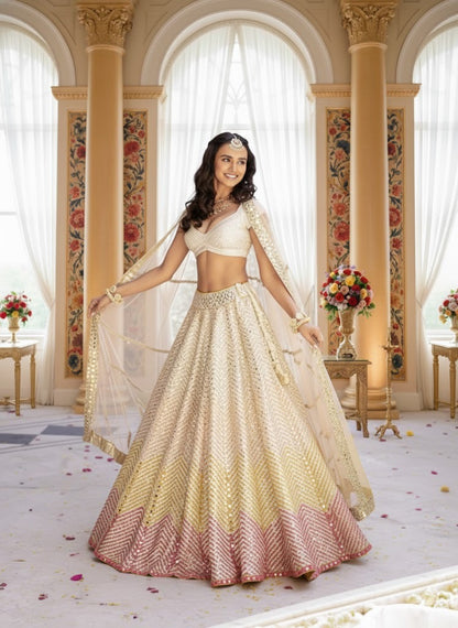 Standing full-length front view of a model in an ivory flared lehenga with yellow and pink ombre chevron hem, paired with a sweetheart choli.