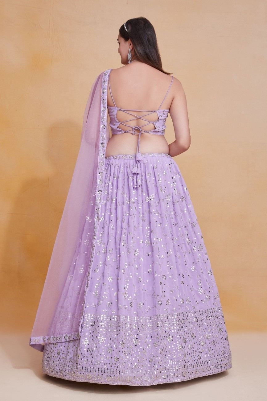 Back view of a model showing the criss-cross lace-up tie detail on a lavender embroidered choli and lehenga skirt.