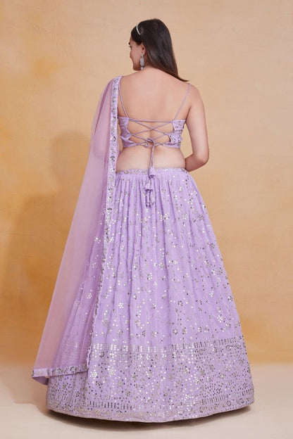 Back view of a model showing the criss-cross lace-up tie detail on a lavender embroidered choli and lehenga skirt.