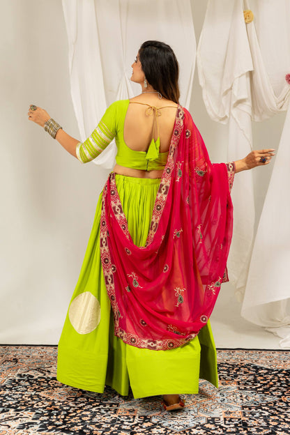 Rear view highlighting the deep scoop back neckline with tie-up tassels on a lime green blouse and draped hot pink dupatta.