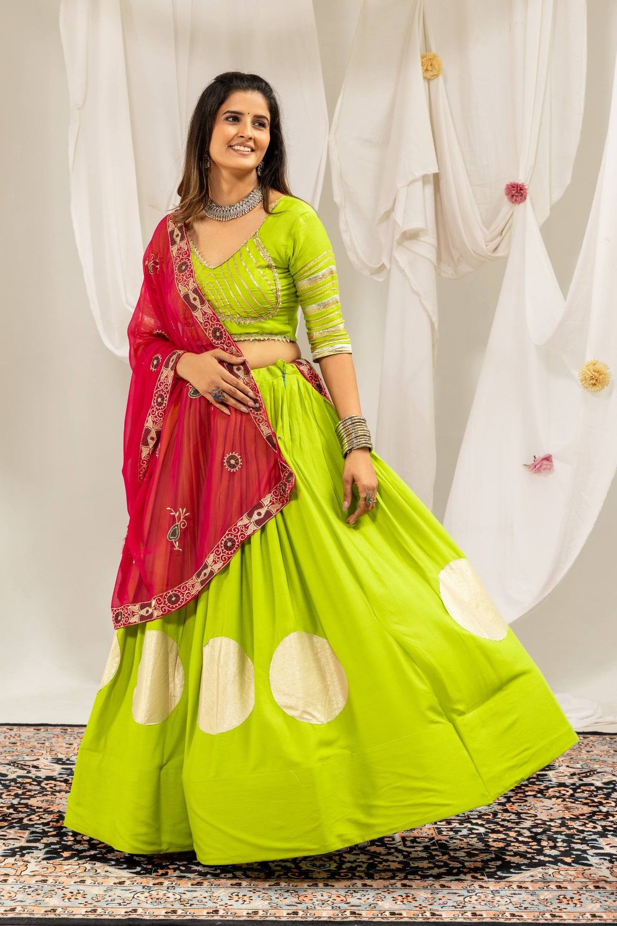 Three-quarter standing pose of a model dressed in a flared lime green lehenga skirt and elbow-sleeve striped choli.