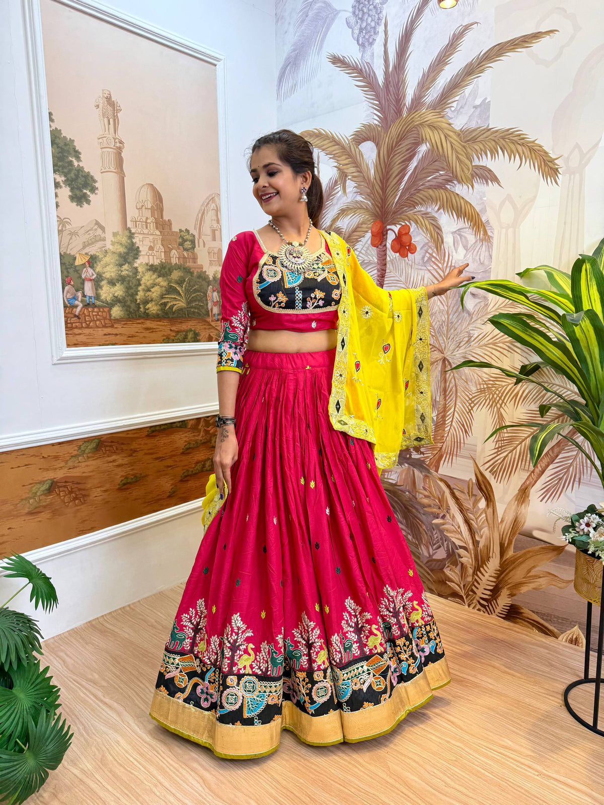Side-angle full-length pose of model showing the wide flare and black printed hem border of a magenta pink lehenga