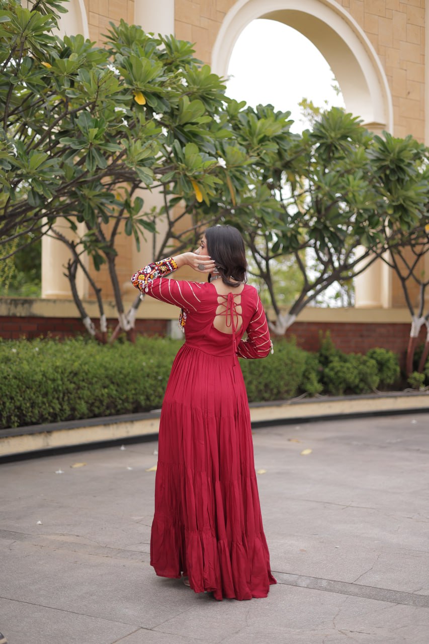 Full-length back view of a maroon tiered flared anarkali gown showing a cut-out back with criss-cross tie-up dori