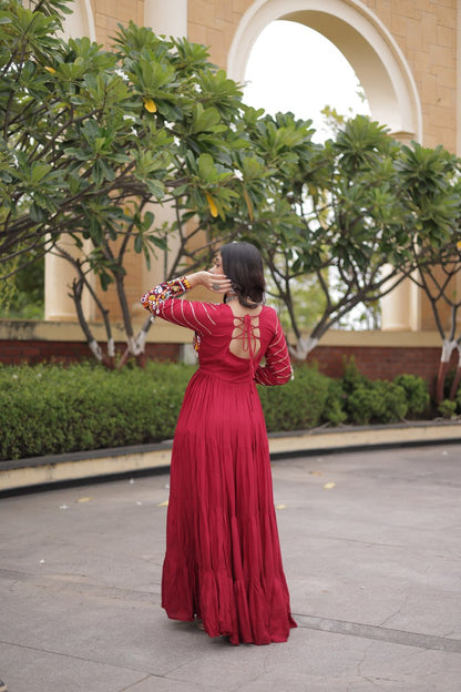 Full-length back view of a maroon tiered flared anarkali gown showing a cut-out back with criss-cross tie-up dori