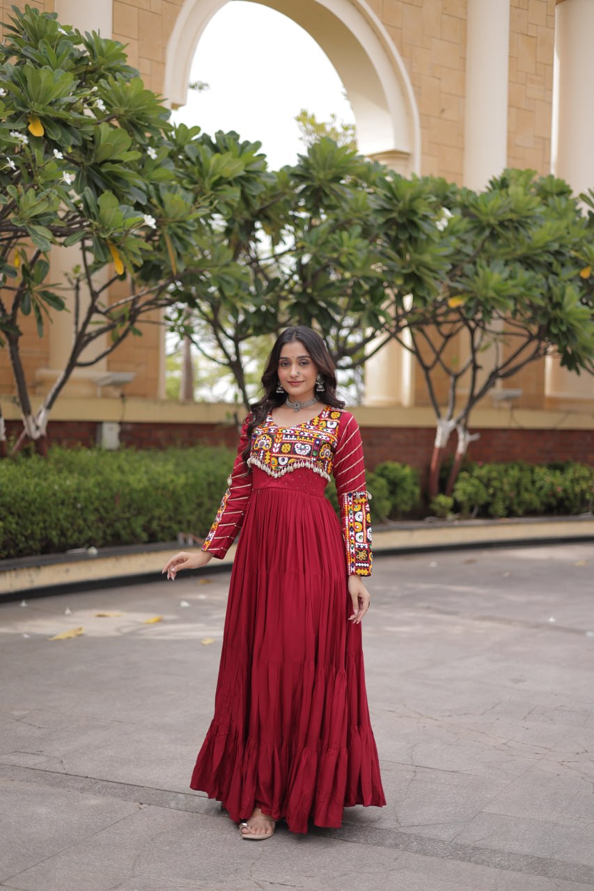 Full-length front view of a model wearing a maroon tiered anarkali dress with embroidered bodice and chevron sleeve pattern