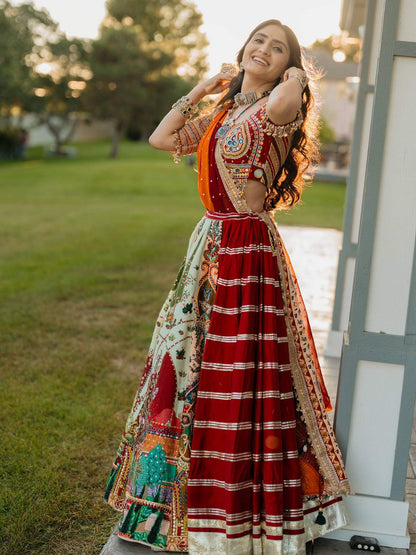 Side view of model in panelled lehenga with red striped gota patti section, pictorial print kali, and embroidered blouse