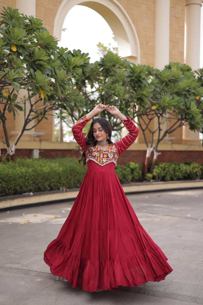 Dynamic full-length pose of model twirling to display the wide gathered tiered flare of a maroon long gown