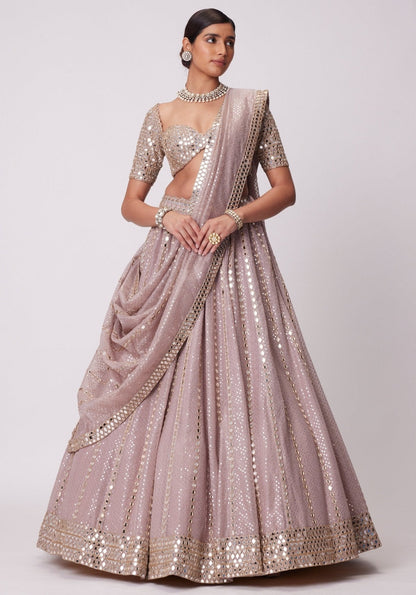 Standing full-length front view of a model in a mauve-pink flared lehenga with vertical mirror lines, matching dupatta drape, and embroidered blouse