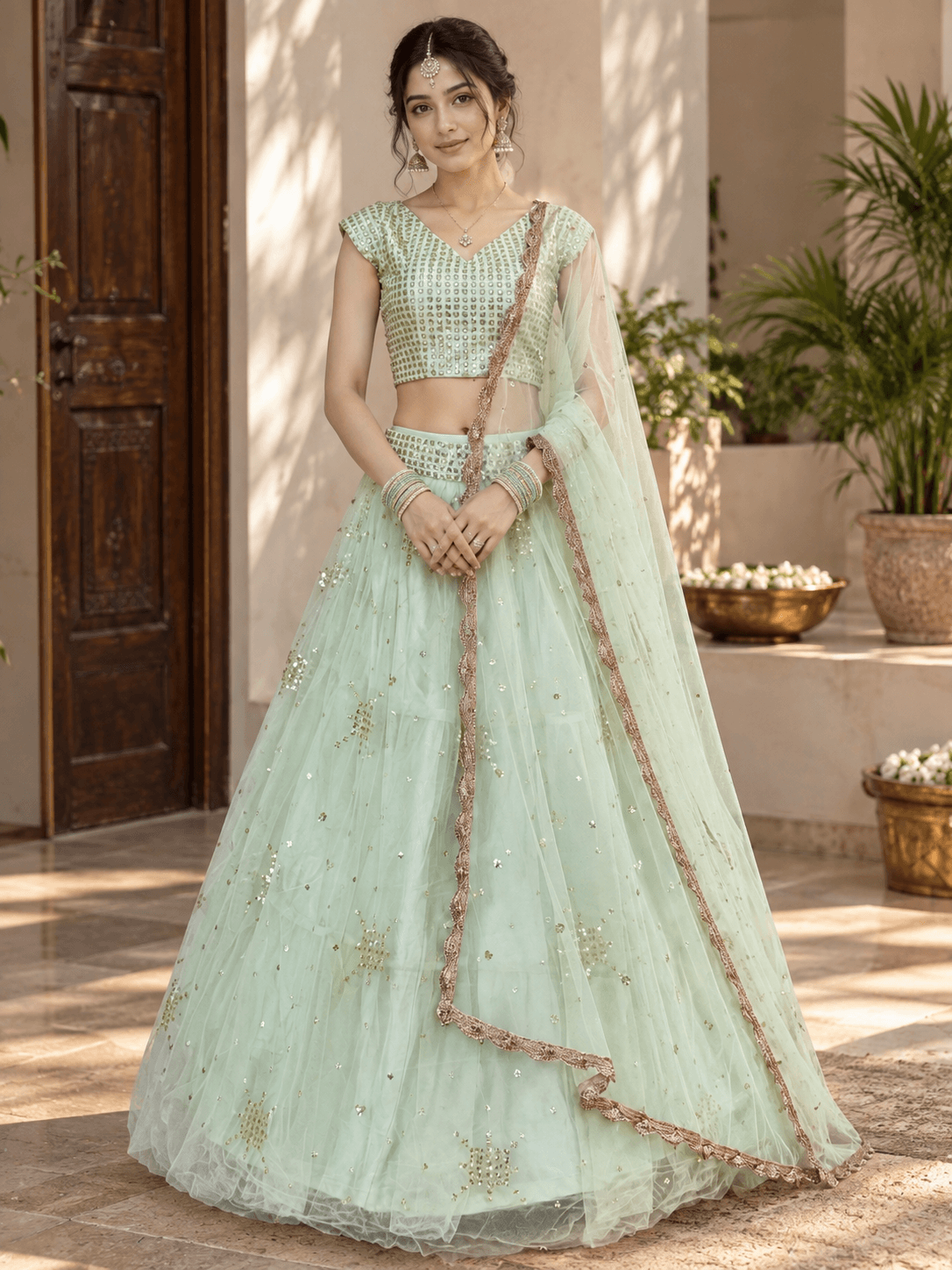 Full front look of a mint green net lehenga choli set paired with a draped border-embroidered dupatta