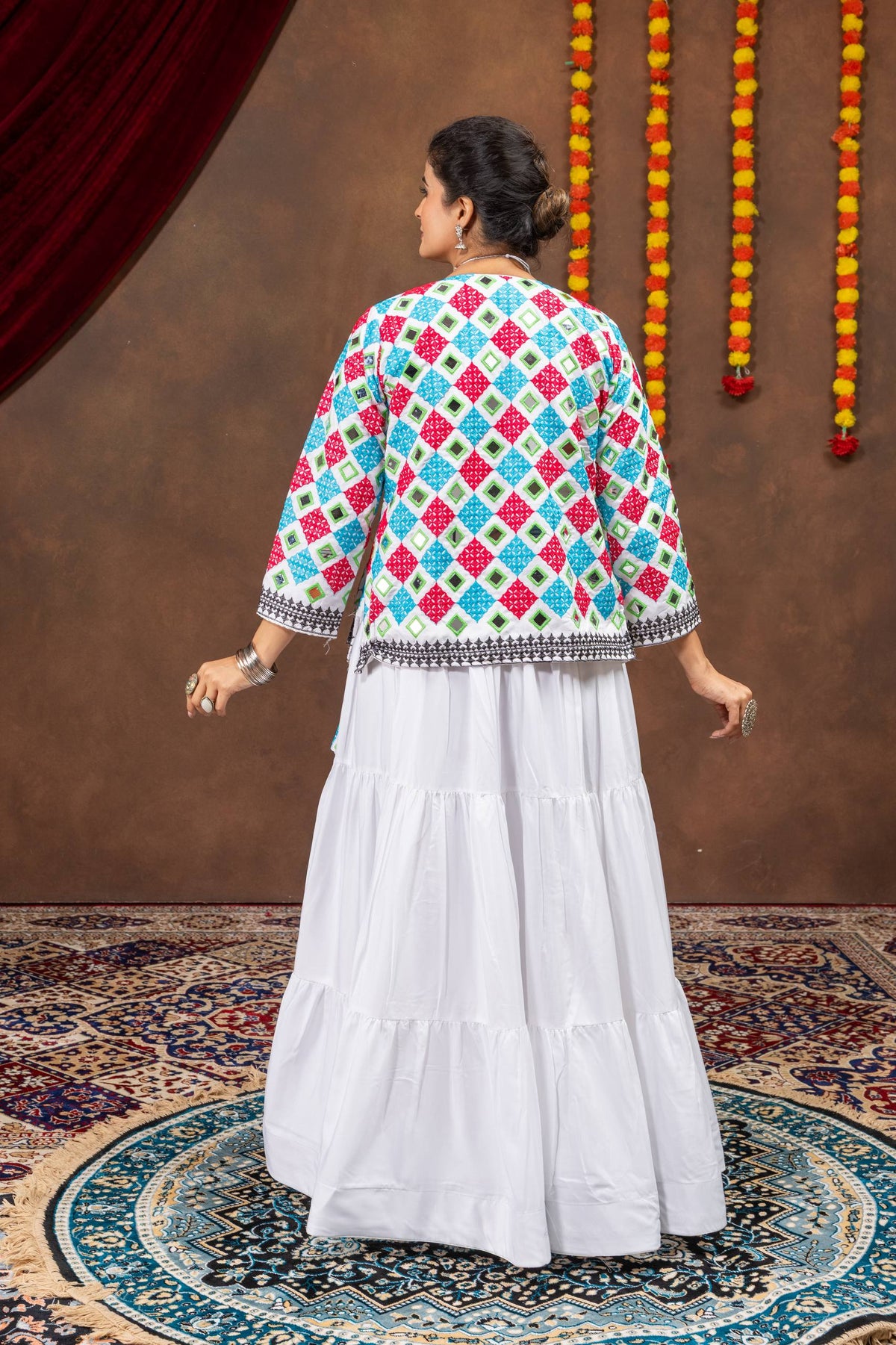 Back view of model wearing full-sleeve white jacket covered in colorful diamond mirror work embroidery