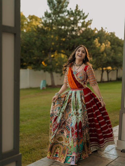 Front walking view displaying the wide flare of a heritage-inspired printed lehenga with red striped panel and orange dupatta