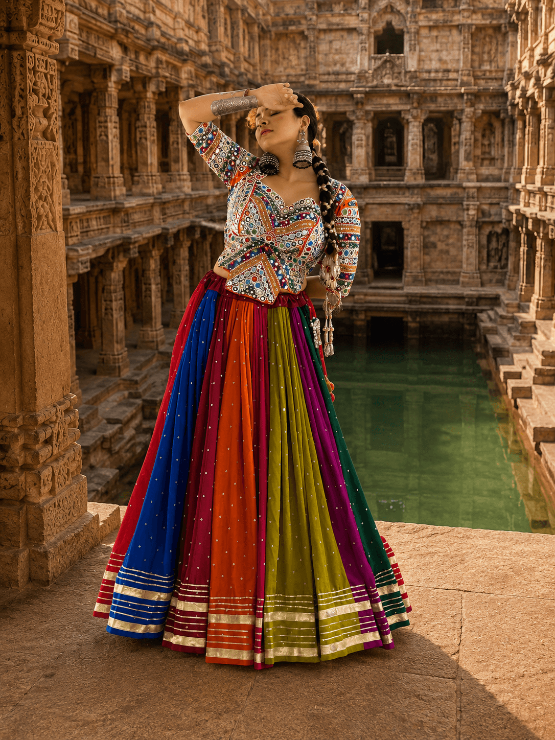 Model in full flare multicolor panelled lehenga showing multi-line gold borders at the hem paired with heavily embroidered choli