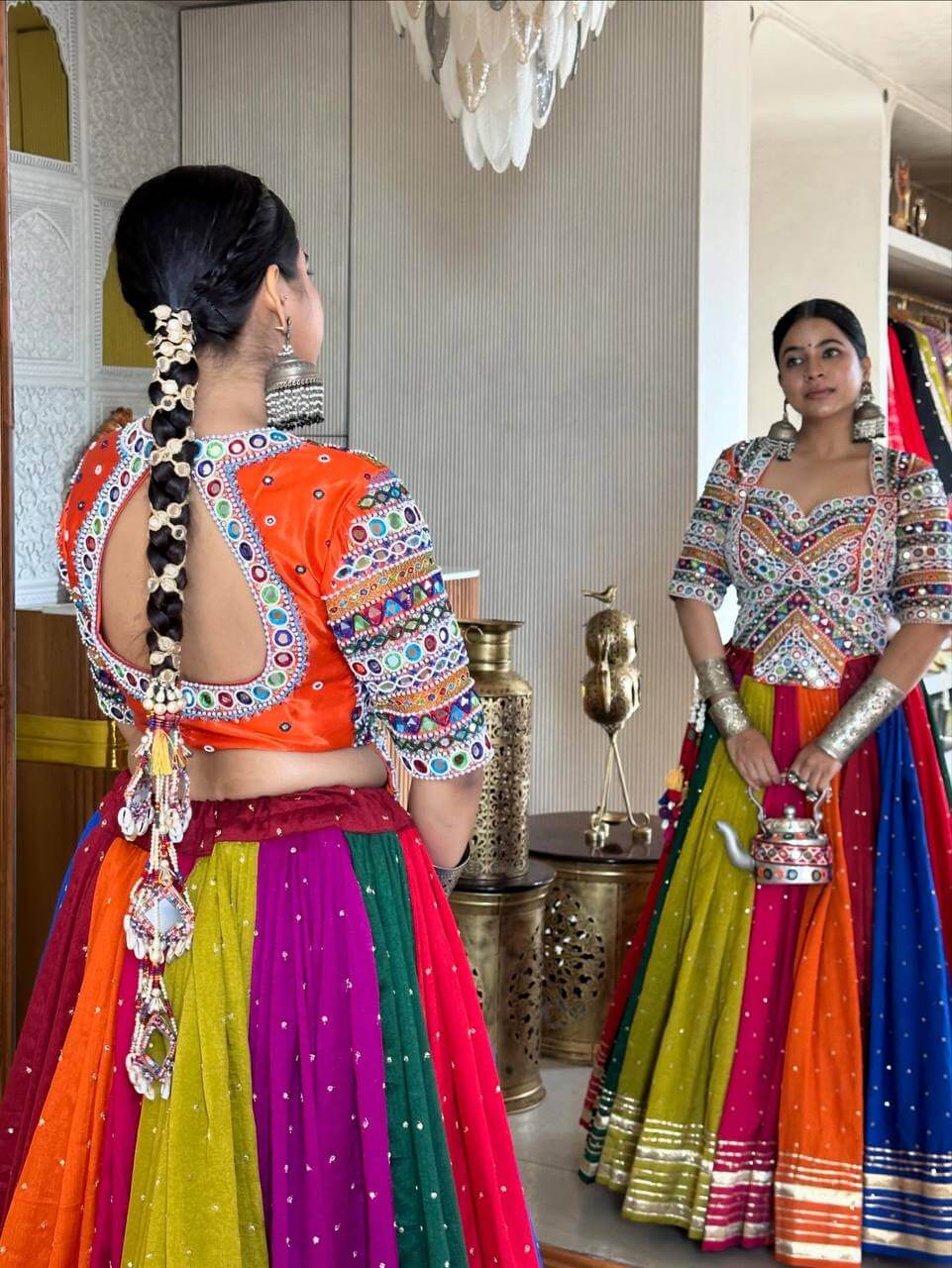 Back view showing keyhole cutout orange blouse with mirror work border paired with a multicolor panelled lehenga