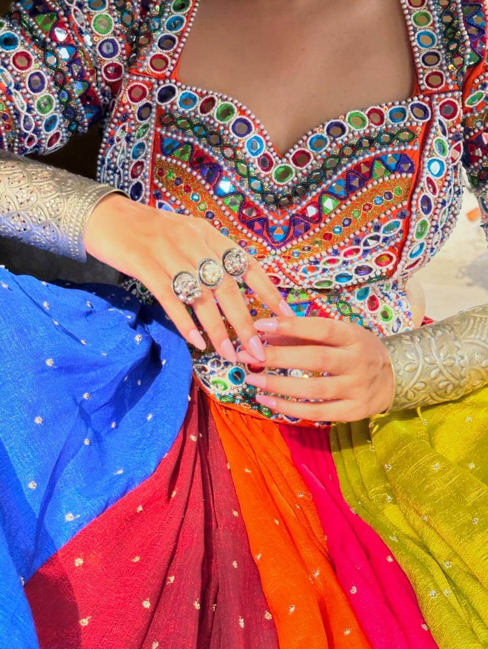 Close-up of multicolor blouse featuring dense mirror work, thread embroidery, and beaded trim
