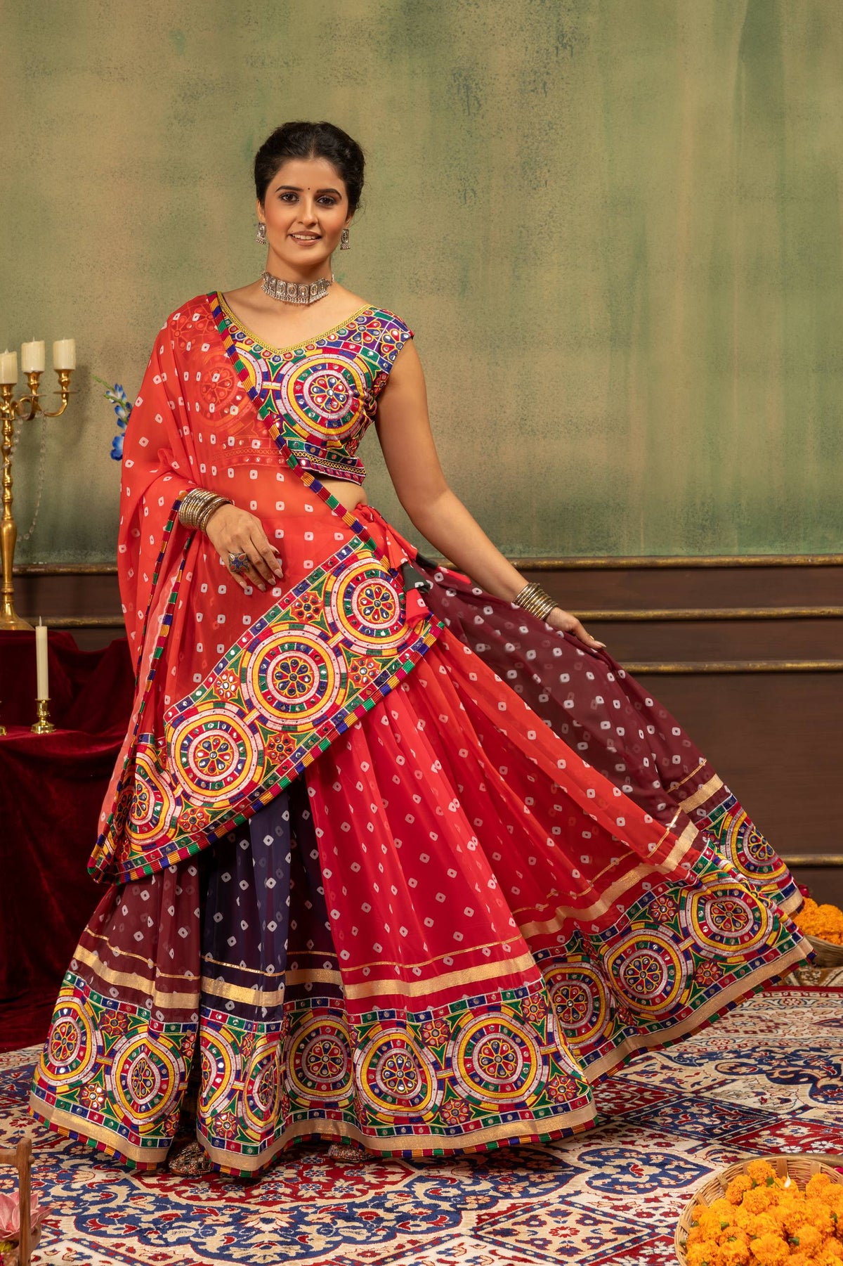 Model lifting side hem of multicolor panelled bandhani lehenga skirt showing wide embroidered border and gota lace