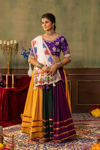 Full-length front view of model wearing yellow, dark green, and purple panelled lehenga skirt with embroidered purple choli